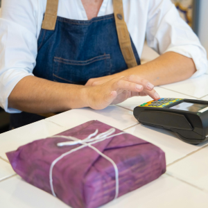 Dependienda con tpv y la compra envuelta en un papel morado