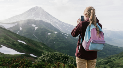 Chica rubia de espaldas en la montaña sacando una foto