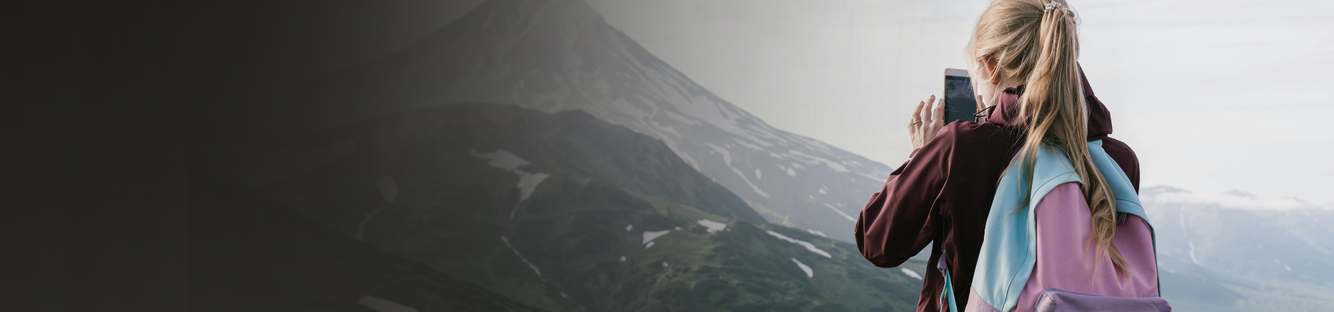 Chica rubia de espaldas sacando foto a monte