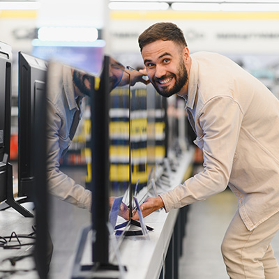Hombre mirando a cámara sonriendo cogiendo una televisión