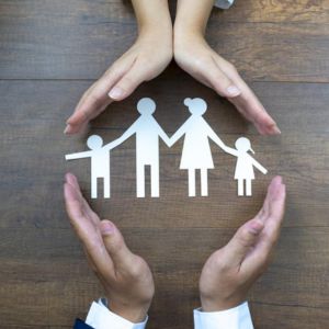 Manos alrededor de un recorte de papel de una familia