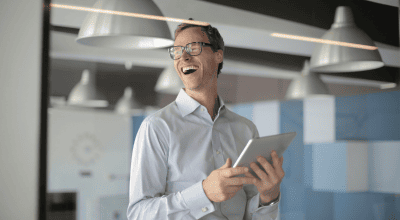 Hombre con camisa en oficina sonriendo con una tablet en las manos