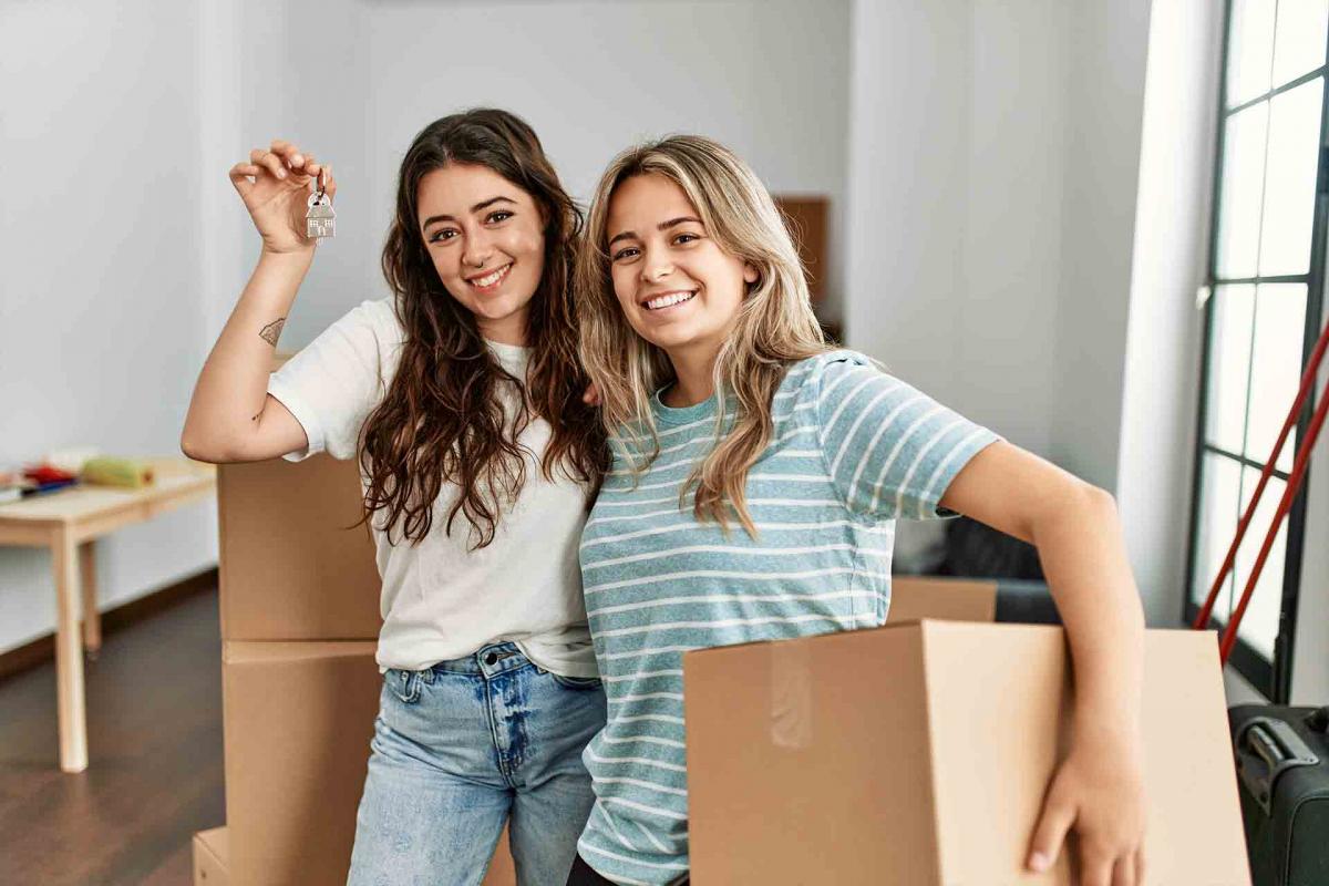 Pareja de mujeres sujetando las llaves de una casa Pareja de mujeres sujetando las llaves de una casa