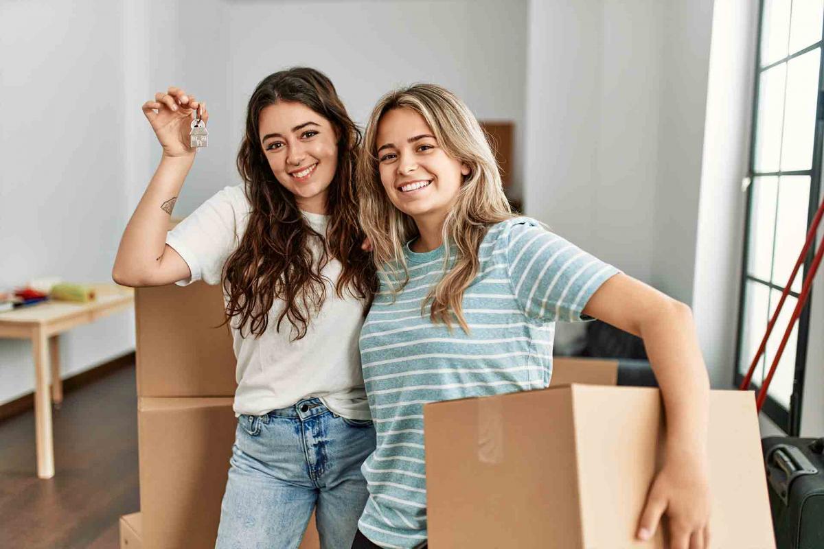 Pareja de mujeres sujetando las llaves de una casa