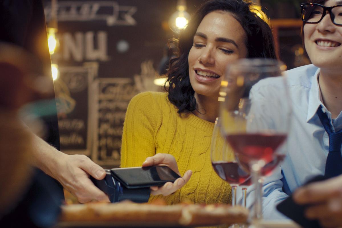 Mujer sonriendo con una copa de vino de fondo