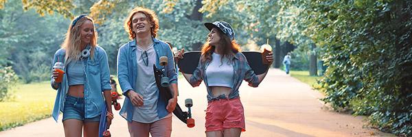 Cuenta y Libreta Joven In - Grupo de jóvenes vestidos con ropa moderna con patinetes, sonriendo junto a un parque rodeado de arboles